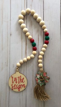 a wooden bead necklace with tassels and an ornament hanging from it's the season