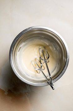 a metal bowl with whisk in it on a table