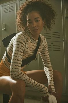 a young woman sitting on top of a locker