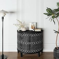 a living room with white walls and wooden floors, two plants on the side table