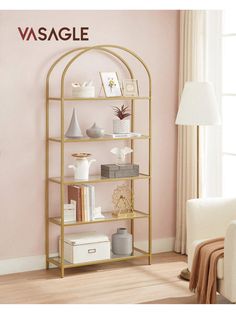 a gold shelf with books and vases on it in front of a pink wall