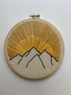 a gold and white embroidered wall hanging with mountains in the background