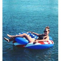 a woman is sitting on an inflatable boat with the american flag painted on it