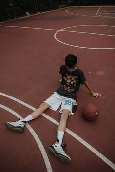 a young boy is sitting on the basketball court