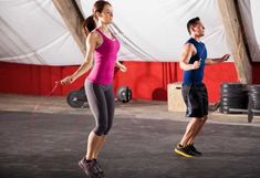 a man and woman are doing exercises in an indoor gym while one holds a jump rope