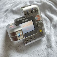 a silver camera sitting on top of a white blanket