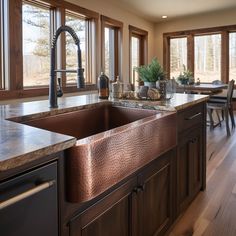 a kitchen with wooden cabinets and large copper sink in front of the window, along with an island countertop