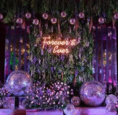 there are disco balls and flowers in front of the neon sign that says forever is ever