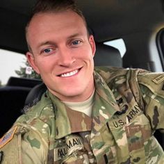 a man in uniform sitting in the back seat of a car smiling at the camera