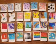 many different colored pictures are displayed on a wooden table with white paper and scissors in front of them