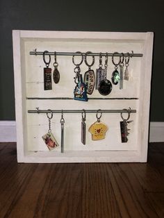 a display case with key chains and various items hanging from it's sides on a wooden floor