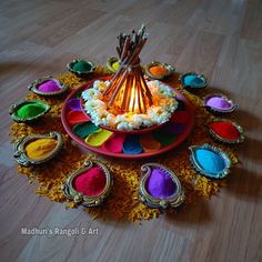 an assortment of colorful powders arranged around a lamp on a wooden table with other items