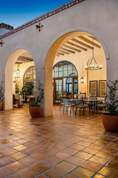 an outdoor dining area with potted plants on the patio and large arched doorways