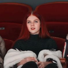 a woman with red hair is sitting in a theater and looking up at the camera