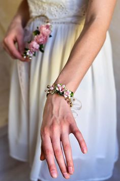 a woman wearing a bracelet with flowers on it's wrist and holding her hand out