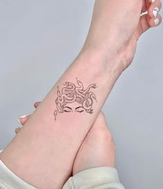 a woman's arm with a tattoo on it that has a small snake on the wrist