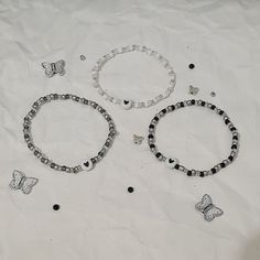 three bracelets and two butterfly charms on a white sheet