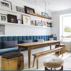 a living room with blue couches and pictures on the wall above it's windows