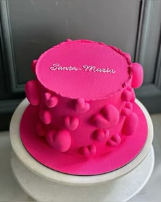 a pink cake with hearts on it sitting on a table