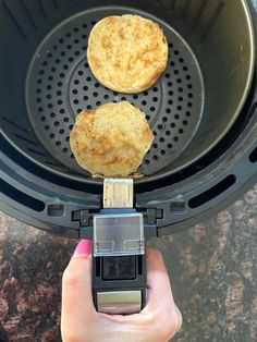 two biscuits are being cooked in an air fryer with the lid open to allow them to cook