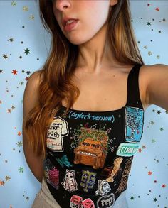 a woman wearing a black tank top with patches on it and stars in the background