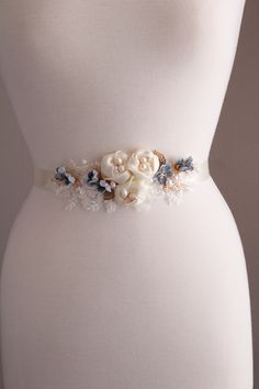 Gold blue  wedding sash Bridesmaid belt Color: gold /ivory/dusky blue with grey accent flowers  Materials:ivory lace , handmade  fabric flowers,blue paper flowers, beads,gold metal leaves, freshwater and faux pearls,wire,satin ribbon. Measurements: Applique approx L 7 inches, W 2.5 inches Applique attached to  ivory satin ribbon 25mm x 260 cm. MORE SASHES: https://www.etsy.com/uk/shop/WeddingJewelryOutlet?ref=seller-platform-mcnav§ion_id=26791561 WEDDING JEWELRY: https://www.etsy.com/uk/shop/WeddingJewelryOutlet?ref=seller-platform-mcnav§ion_id=26786154   MATCHING HEADPIECES: https://www.etsy.com/uk/shop/WeddingJewelryOutlet?ref=simple-shop-header-name&listing_id=724957245§ion_id=26785826 *Please NOTE colors may be slightly different than the monitor shows due to monitor differences. Some Elegant Blue Sashes For Wedding, Elegant Blue Bridal Belt For Wedding, White Adjustable Wedding Sashes, Elegant Bridal Belt With Flower Decoration For Wedding, Adjustable Bridesmaid Bridal Belt With Sashes, Adjustable Bridal Belt With Sashes For Bridesmaid, Elegant Bridal Belt With Handmade Flowers For Weddings, Adjustable White Bridal Belt For Bridesmaid, Gold Bridal Dress