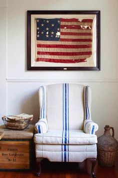 an american flag hanging on the wall next to a white chair with blue and white stripes