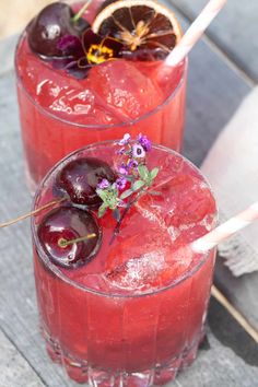 two glasses filled with red liquid and cherries