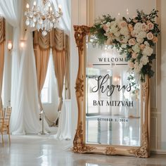 a welcome sign is displayed in front of a mirror with flowers and greenery on it