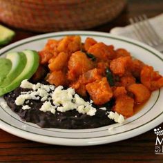 a white plate topped with black beans and avocado