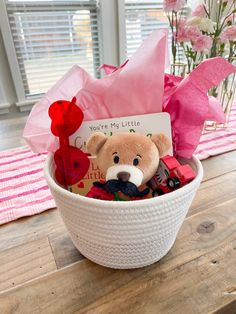 a teddy bear sitting in a white basket with pink flowers and a card that says you're my little