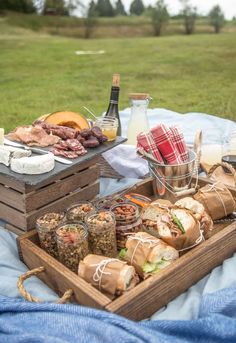 a picnic table with food and wine on it in the park, near a man running