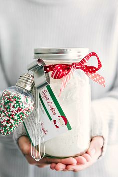 a person holding a mason jar filled with white and red sprinkles