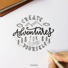 someone is writing on paper that says create adventures for yourself with trees and mountains in the background