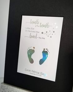 a baby's hand and foot prints are displayed in a black frame on a shelf