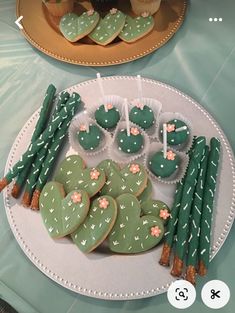 two plates with cactus cookies on them and cupcakes in the shape of hearts