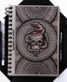 a spiral notebook with a drawing of a snake on the front and skull on the back