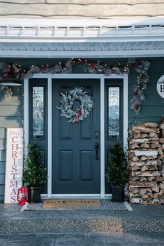 a blue front door decorated with christmas wreaths and pineconi trees for the holiday season