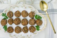 a white plate topped with meatballs on top of a table next to a spoon