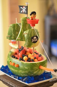 a watermelon boat filled with lots of fruit and pirate flags on top of it