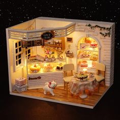 a miniature model of a bakery with lights on and food in the display case,