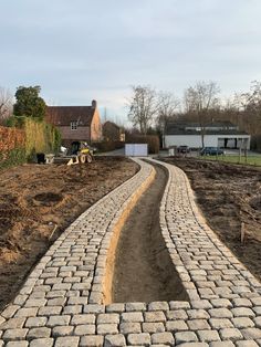 a brick path in the middle of a field with construction equipment on top of it