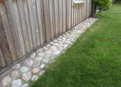 there is a stone path between the grass and a wooden fence with a window on it