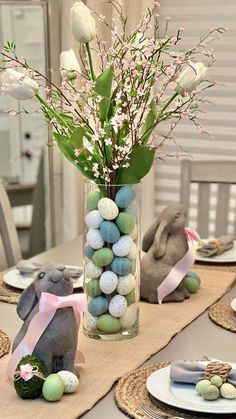 a vase filled with eggs sitting on top of a table next to plates and flowers