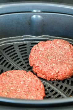 two hamburger patties cooking in an air fryer