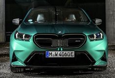 the front end of a green car parked in a parking lot next to a building