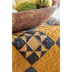 a wooden bowl filled with vegetables on top of a quilted tablecloth covered table