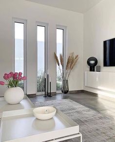 a modern living room with white furniture and flowers in vases on the coffee table