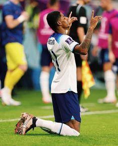 a soccer player sitting on the ground with his hand up