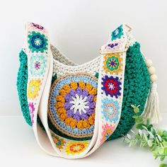 a crocheted purse sitting on top of a white table next to a plant